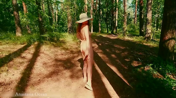 a nudist girl walks in forest near the beach among dressed emerald ocean